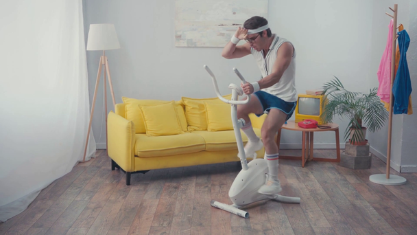 Täyspitkä urheilija silmälaseissa harjoittelu kuntopyörä kotona - Materiaali, video