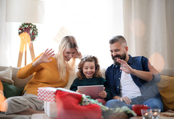 Family with small daughter indoors at home at Christmas, having video call. - Fotoğraf, Görsel