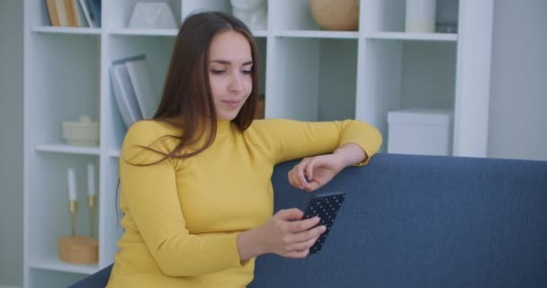 Detailní portrét příjemné ženy středního věku se světlými vlasy, která leží v kanceláři, leží na pohovce a mluví na videu v telefonu doma, drží ho na délku paže - Záběry, video