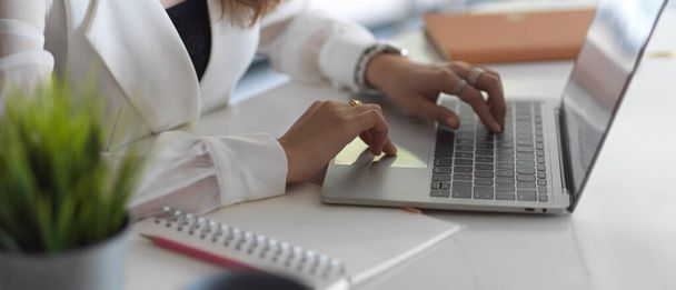 Oldalnézet üzletasszony kezét gépelés laptop billentyűzeten, miközben dolgozik irodai íróasztal  - Fotó, kép