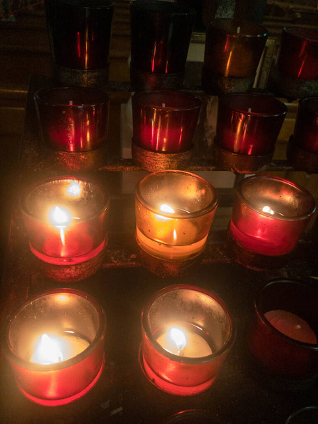Red votive candles flicker in a Catholic church. - Photo, Image