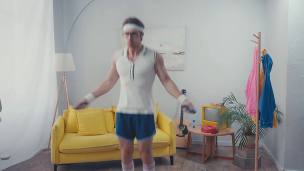 Sportler mit Brille springen Seilspringen im Wohnzimmer, Retro-Sportkonzept - Filmmaterial, Video