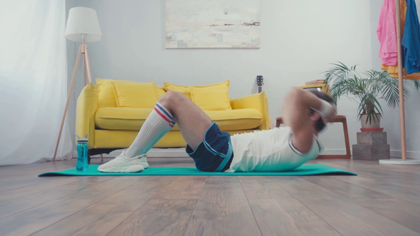 Povrchová úroveň sportovce dělat sedy up na fitness podložku v obývacím pokoji - Záběry, video