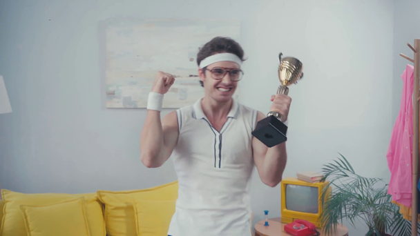 Портрет возбужденного спортсмена, позирующего с наградой во время фотовспышек дома - Кадры, видео