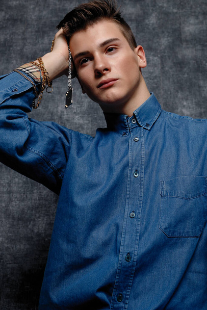 Man in denim shirt, arms on hips, gray background. People lifestyle concept. Mock up copy space. Straightening sleeves looking aside. face close up - Valokuva, kuva