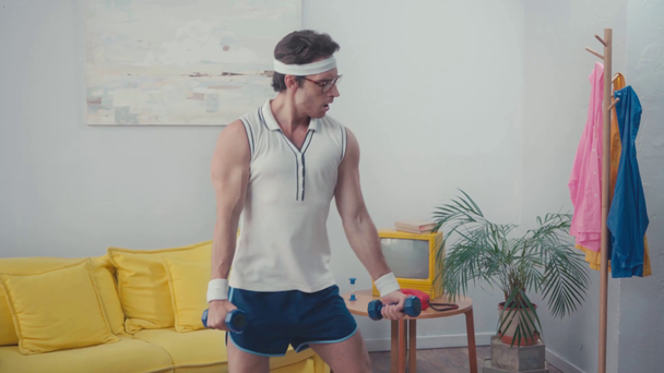 Sportsman squatting, while lifting weight at home, retro sport concept - Footage, Video