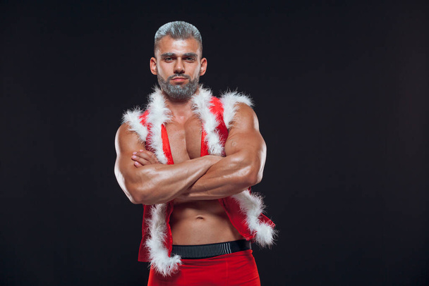 Sexy Santa Claus . Young muscular man wearing Santa Claus hat demonstrate his muscles. Isolated on black background. - Foto, Imagem