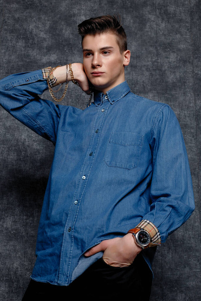 Man in denim shirt, arms on hips, gray background. People lifestyle concept. Mock up copy space. Straightening sleeves looking aside - Valokuva, kuva