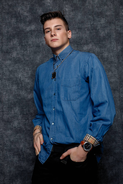 Man in denim shirt, arms on hips, gray background. People lifestyle concept. Mock up copy space. Straightening sleeves looking aside. hands on the belt - Foto, Imagen
