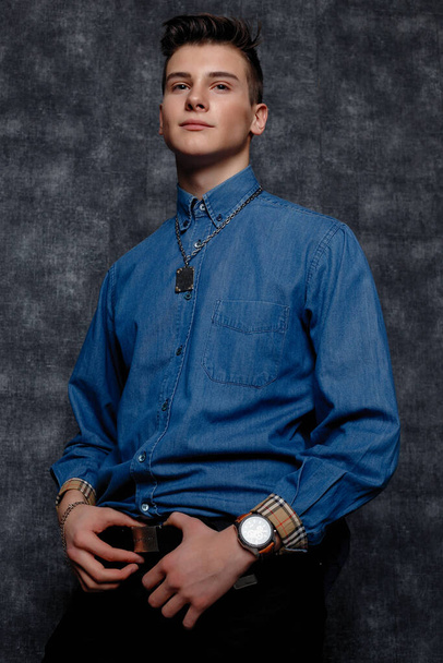 Man in denim shirt, arms on hips, gray background. People lifestyle concept. Mock up copy space. Straightening sleeves looking aside. hands on the belt - Foto, afbeelding