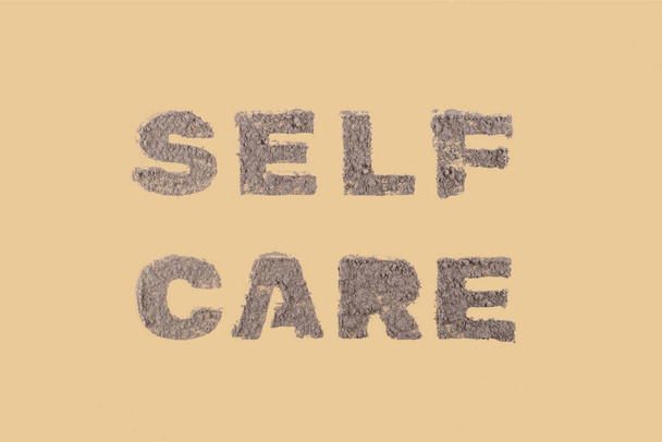 Self care an inscription on a beige neutral background made of natural clay for a face and body skin mask. Top view, flat lay - Photo, Image