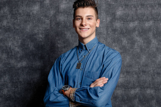 Man in denim shirt, arms on hips, gray background. People lifestyle concept. Mock up copy space. Straightening sleeves looking aside. smile - Zdjęcie, obraz