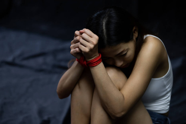 Zastavte násilí na ženách. Oběti ženy svázané červeným provazem. Sexuální zneužívání nebo znásilnění v tmavé místnosti - Fotografie, Obrázek