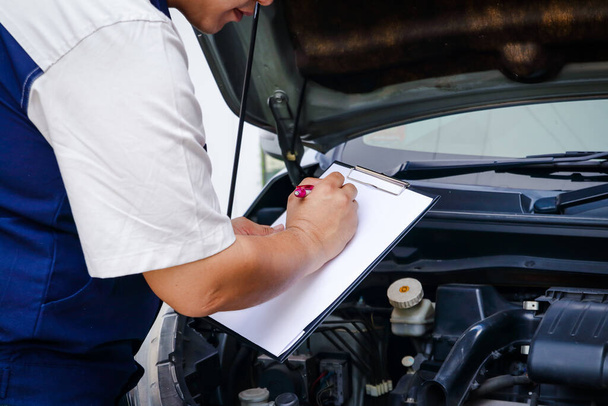 The car mechanic is recording the checklist of the car's bad condition. - Photo, Image