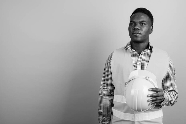 Studio záběr mladého afrického muže stavební dělník proti bílému pozadí v černobílé - Fotografie, Obrázek
