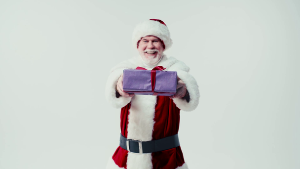 happy santa claus presenting gift box while smiling at camera isolated on white - Materiał filmowy, wideo