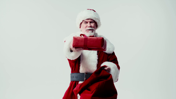 έκπληκτος Άγιος Βασίλης πάρει κουτί δώρου από σακί που απομονώνονται σε λευκό - Πλάνα, βίντεο