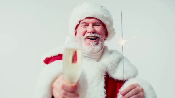 Ευτυχισμένος Άγιος Βασίλης που κρατάει σπίθα και ένα ποτήρι σαμπάνια απομονωμένο στο λευκό - Πλάνα, βίντεο