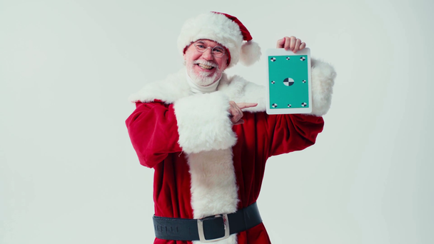wesoły Święty Mikołaj celujący w tabletkę i kiwającą głową odizolowany na biało - Materiał filmowy, wideo