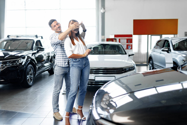 Young happy couple just bought a new car in a dealership - Foto, afbeelding