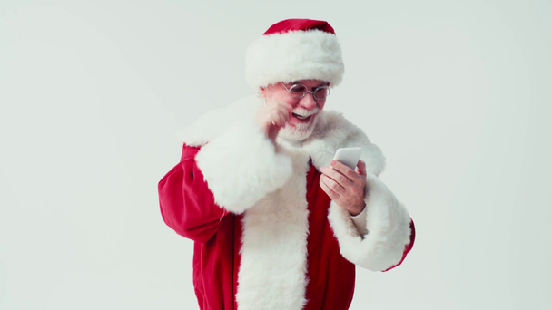 Babbo Natale chatta su smartphone e tocca occhiali isolati su bianco - Filmati, video