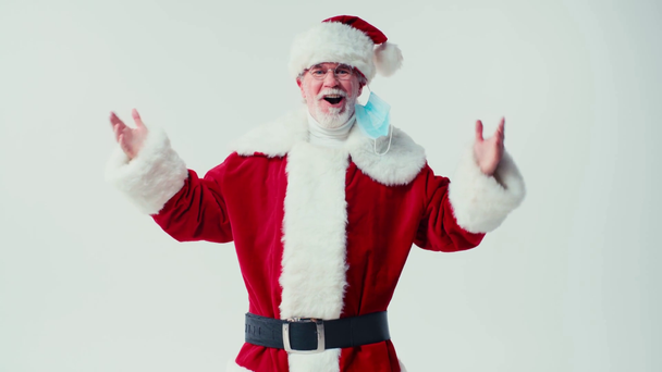 Санта Клаус снимает медицинскую маску и смеется изолированно на белом - Кадры, видео