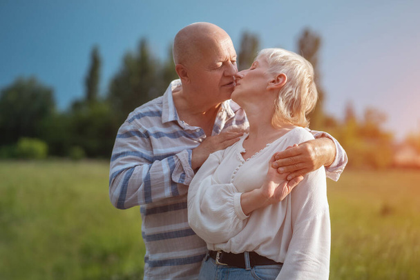 happy senior couple dating, hugging and kissing outdoor at sunset - Фото, зображення