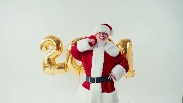 Weihnachtsmann spaziert mit Luftballons in Form eines Weihnachtsmannes auf weißem Grund - Filmmaterial, Video
