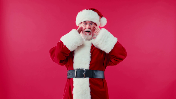 σοκαρισμένος Άγιος Βασίλης αγγίζοντας πρόσωπο απομονώνονται σε κόκκινο - Πλάνα, βίντεο