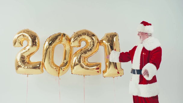 santa claus with sparkler pointing at balloons in 2021 shape isolated on white - Footage, Video