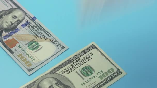 Le banconote da cento dollari cadono sul tavolo blu. Il concetto di ricchezza e prosperità. - Filmati, video