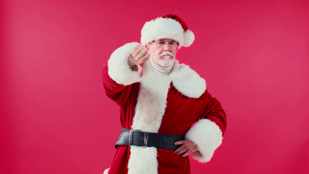 disgustado Santa Claus con la mano en la cadera mostrando el pulgar hacia abajo aislado en rojo - Metraje, vídeo