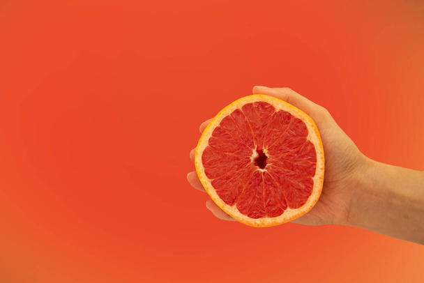 The hand holds half of the grapefruit in the background - Foto, Bild