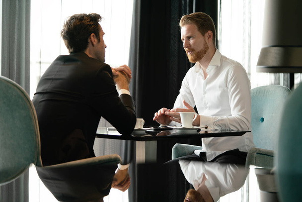 Image of young businessman with cup of coffee communicating with his colleague - Valokuva, kuva