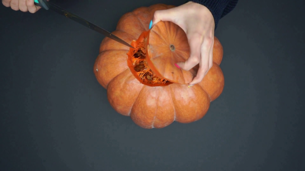 top view of tattooed woman holding knife and carving ripe pumpkin on black - Materiaali, video