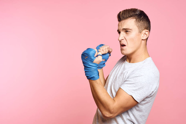 Guy in blue gloves on a pink background are boxing in a white t-shirt cropped view - Foto, Imagen