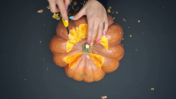top view of woman carving ripe and creepy pumpkin on black - Footage, Video