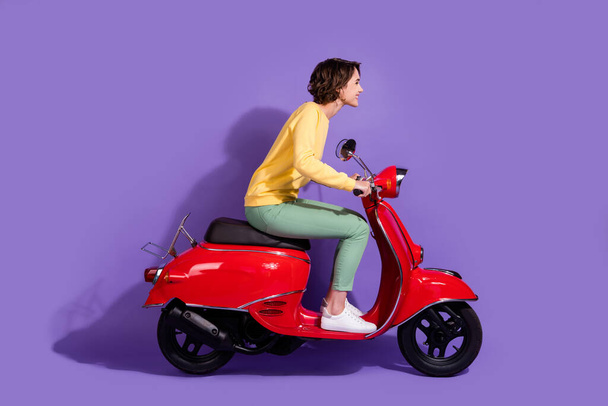 Full length body size side profile photo of young girl wearing casual outfit driving red motorcycle smiling looking forward isolated on vivid purple color background - Fotografie, Obrázek
