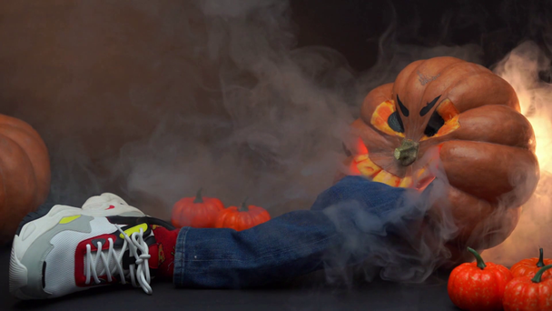 smoke near creepy pumpkins and fake leg in jeans on black - Footage, Video
