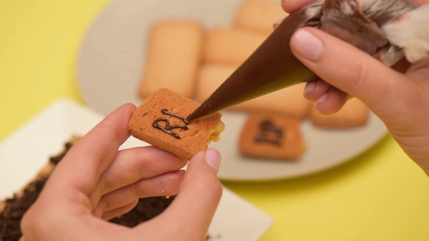 rack focus of woman squeezing rip liternictwo z czekolady w torbie cukierniczej - Materiał filmowy, wideo