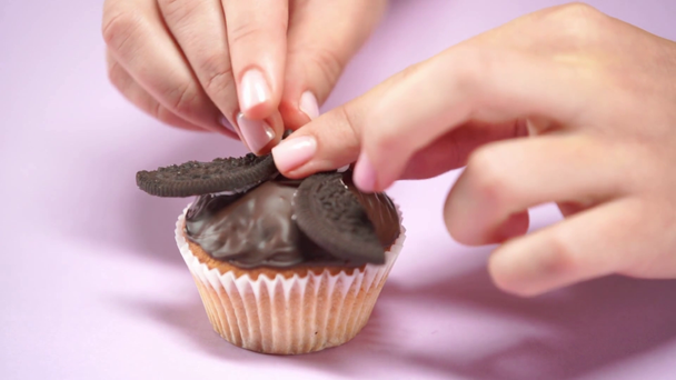 przycięty widok kobiety wprowadzenie słodkie dekoracyjne oczy na czekoladowe babeczki - Materiał filmowy, wideo