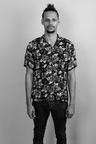 スタジオショットの若いですbeadedハンサムなアフリカ人男性身に着けていますハワイアンシャツに対してグレー背景で黒と白 - 写真・画像