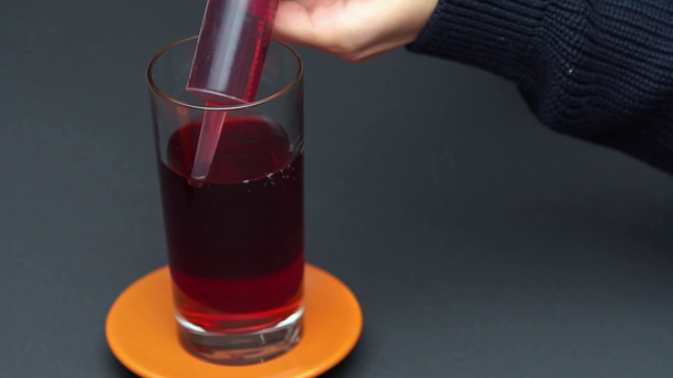 ガラスの赤い液体でお菓子の注射器を満たす女性のクロップドビュー - 映像、動画