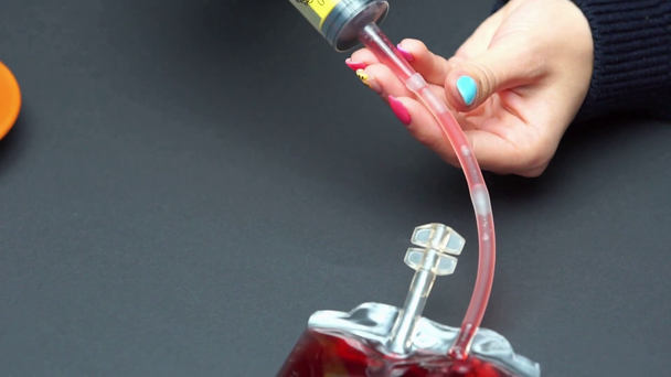 skupienie uwagi kobiety napełniającej strzykawkę ze słodyczami płynem z opakowania z krwią - Materiał filmowy, wideo