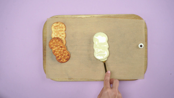 обрізаний вид жінки, що занурює печиво в вершки в миску на світло-фіолетовому
 - Кадри, відео