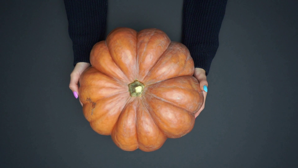 cropped view of woman putting ripe pumpkin on black surface - Footage, Video