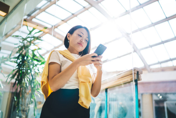 Pretty asian female in smart casual wear holding smartphone connected to 4G internet typing and sending text messages,businesswoman using banking app on mobile phone making money transaction - 写真・画像