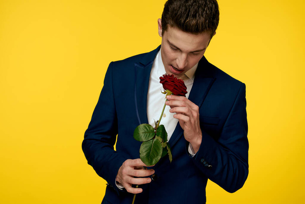 Gentleman in classic suit on yellow background with red rose romance  - Photo, image