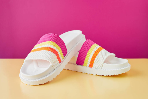 Pair of colorful multicolored rainbow flip flops or sandals on pastel background. Beach holidays and Summer concept with copy space. - Foto, Imagen