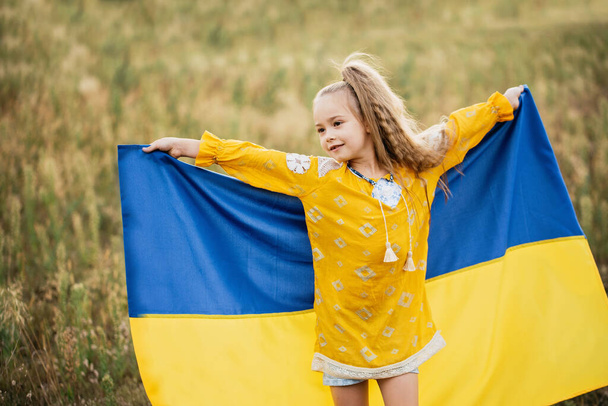 Meisje blauwe en gele vlag van Oekraïne in het veld. Oekraïense Onafhankelijkheidsvlag Dag. Grondwettelijk dag. 24 augustus. Patriottische vakantie. - Foto, afbeelding